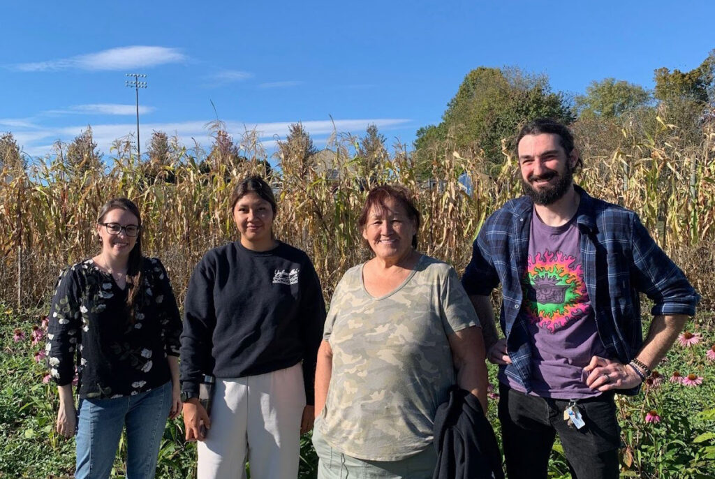 Katelyn Lucas, Victoria and Theresa Johnson, and Kyle Keeler posing in front of a corn field.